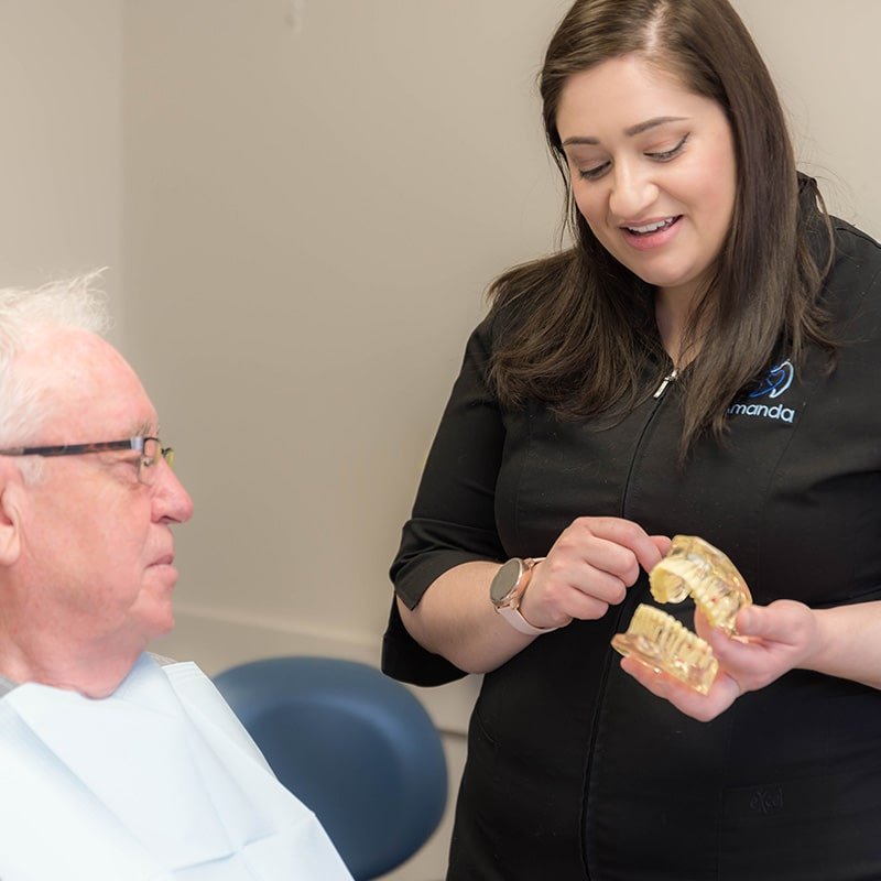 An older patient discussing Dental Implant options with Calgary Dental Assistant